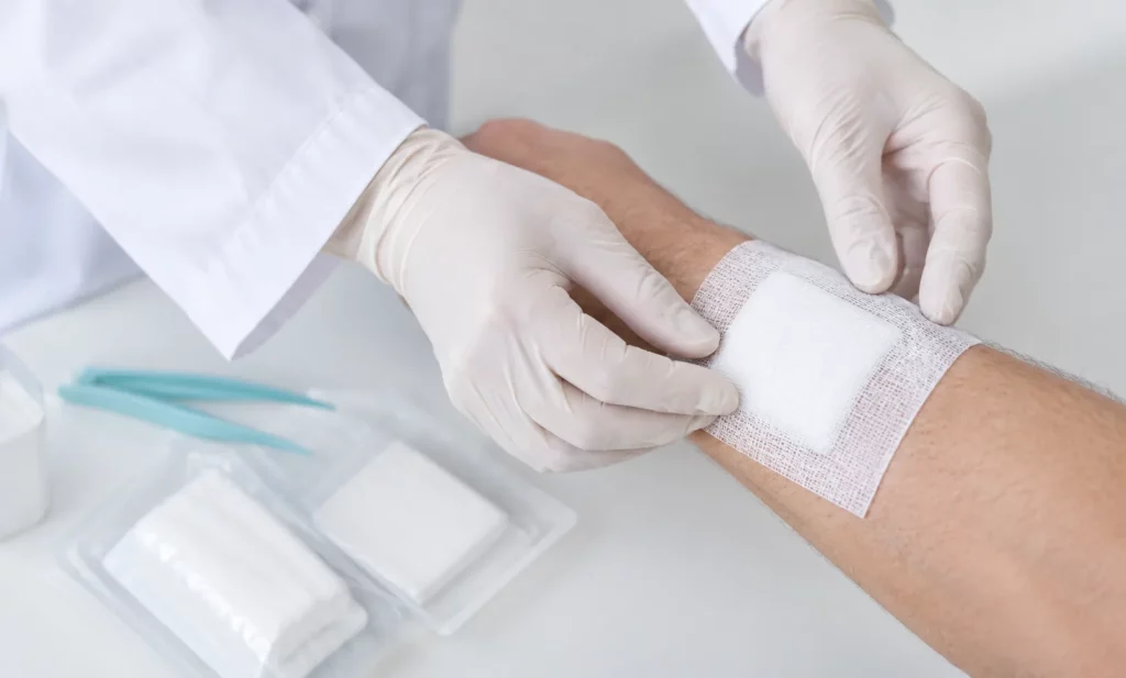 Infirmière posant un pansement sur l’avant-bras d’un patient